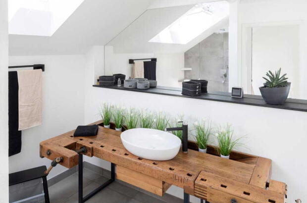 Helles Badezimmer mit zwei Dachfenstern und Holztisch - Velux Magazin