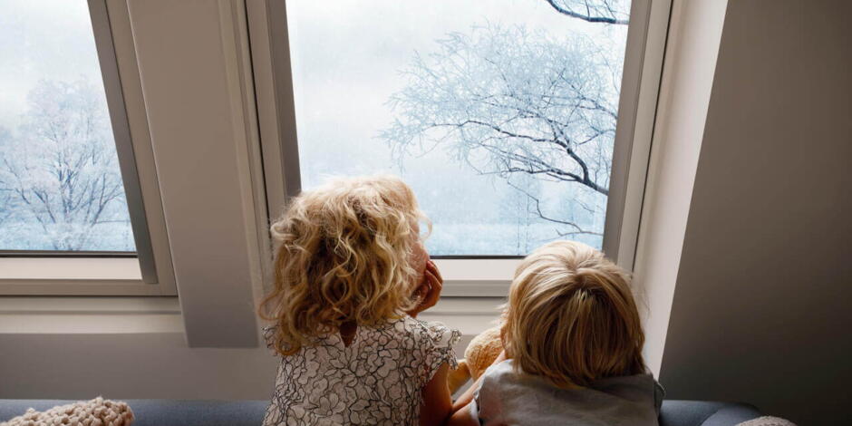 Kinder gucken durch ein Dachfenster auf Schnee | VELUX Magazin