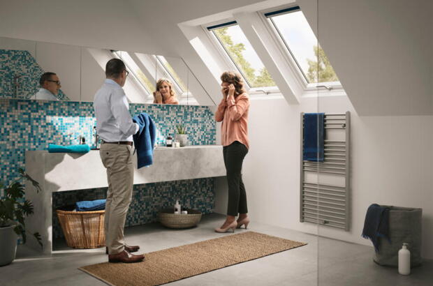 Paar steht im Badezimmer mit Mosaik-Wand und zwei Dachfenstern - Velux Magazin