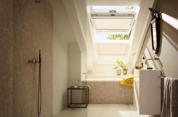 Salle de bains avec un bandeau lumineux VELUX au-dessus de la baignoire - Magazine VELUX