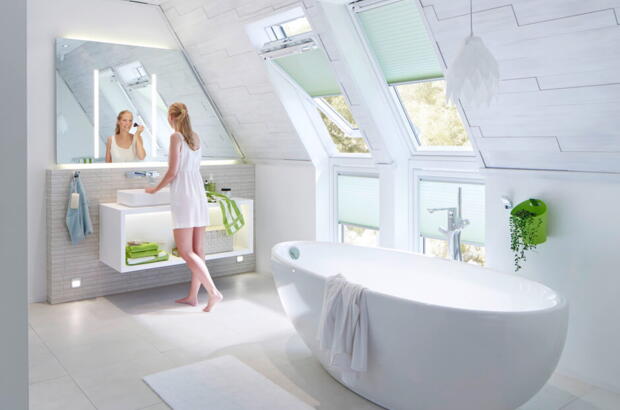 Une femme se maquille dans sa salle de bains avec deux solutions d'éclairage Velux Mur | Magazine VELUX