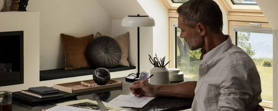 Mann arbeitet am Schreibtisch unter Dachschräge mit Lichteinfall | VELUX Magazin
