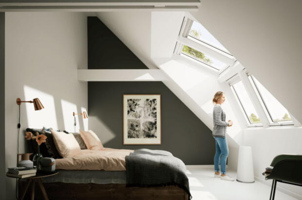 Frau steht im Schlafzimmer mit einer grossen VELUX Panorama Lichtlösung -  VELUX Magazin