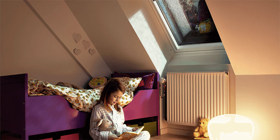 Un bambino legge un libro in un salotto sotto un tetto spiovente | Rivista VELUX