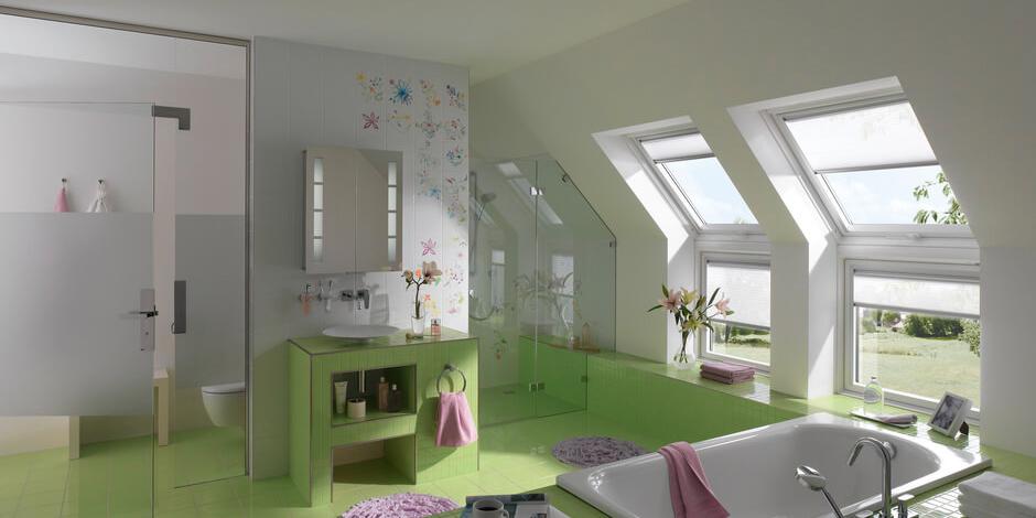 Une salle de bains avec une pente de toit peut tout à fait être aménagée de manière attrayante, comme le montre cette salle de bains carrelée en vert avec les grandes combinaisons de fenêtres. | Magazine VELUX